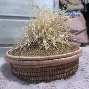 A lidded woven basket with a straw topper